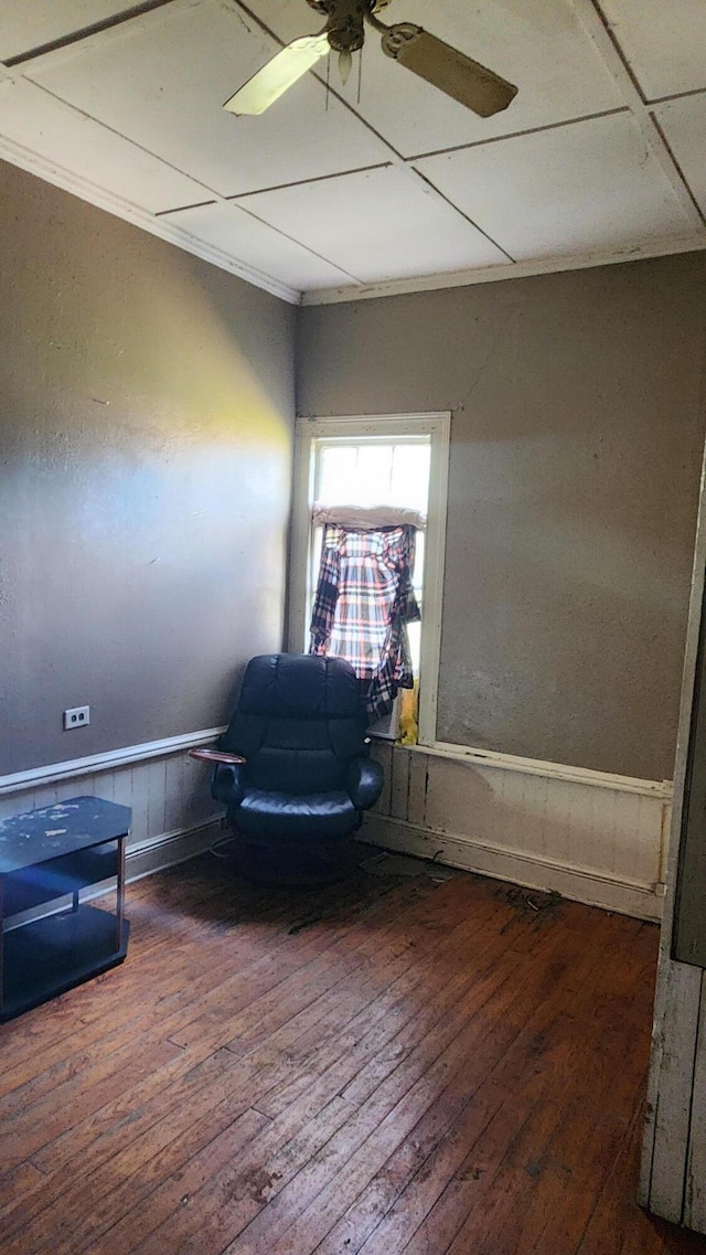 sitting room with hardwood / wood-style flooring, ceiling fan, and wainscoting