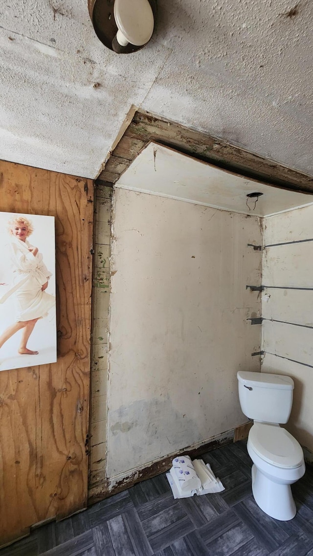 bathroom featuring wood walls and toilet