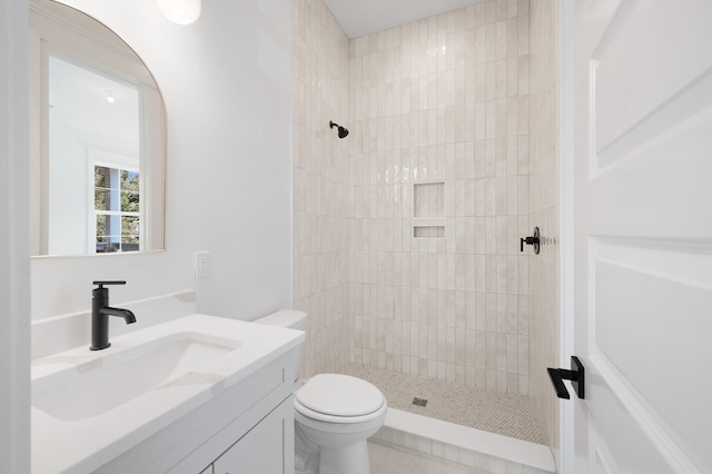 bathroom with vanity, toilet, and a tile shower