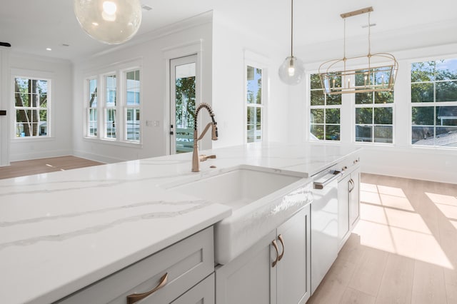 kitchen featuring light stone countertops, light hardwood / wood-style floors, white dishwasher, and sink