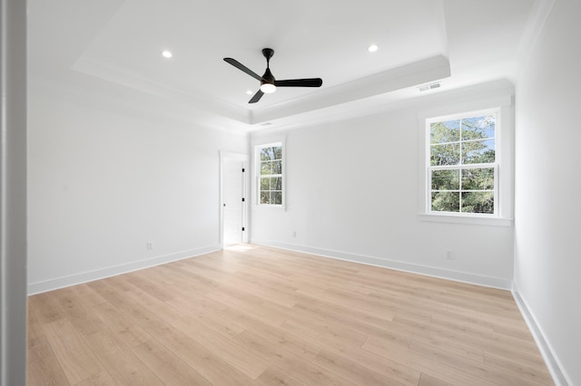 spare room with ceiling fan, a raised ceiling, and light wood-type flooring