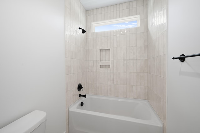 bathroom featuring tiled shower / bath combo and toilet