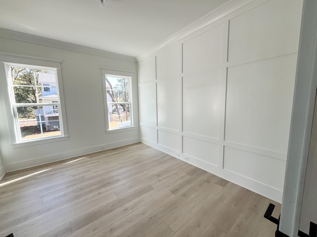 empty room with ornamental molding and light hardwood / wood-style flooring