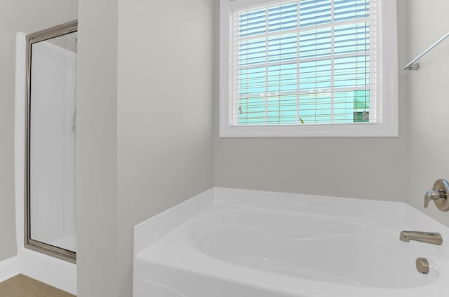 full bath with a garden tub, a healthy amount of sunlight, and a shower stall