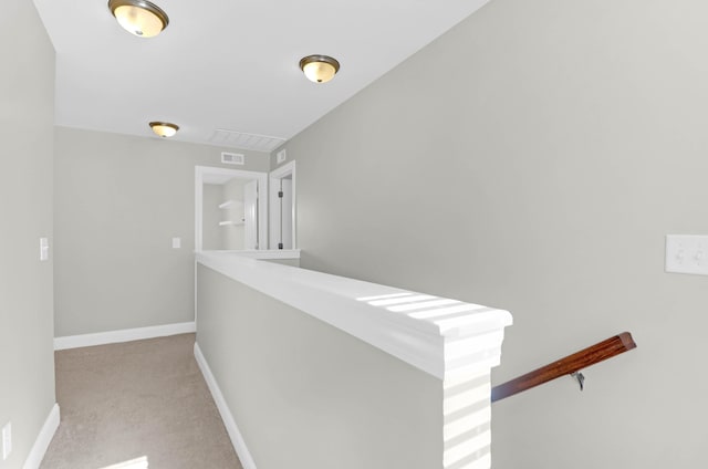 hallway featuring light colored carpet, baseboards, and visible vents