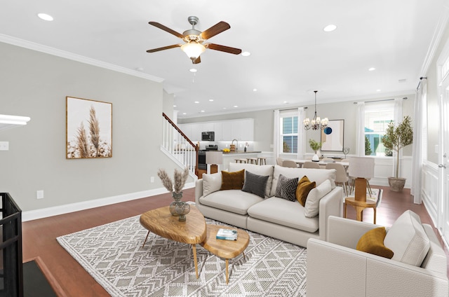 living area with crown molding, recessed lighting, ceiling fan with notable chandelier, and stairway