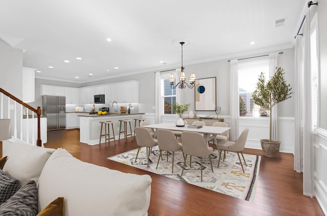 dining area with crown molding, an inviting chandelier, dark wood-style flooring, and visible vents