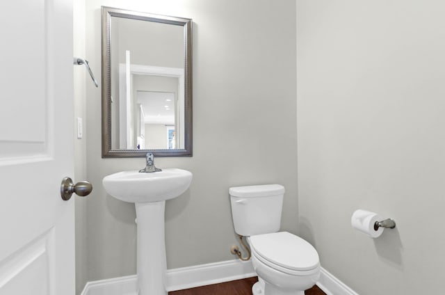 bathroom featuring baseboards, wood finished floors, and toilet