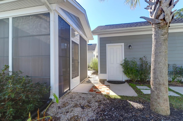 view of property exterior featuring roof with shingles and a sunroom