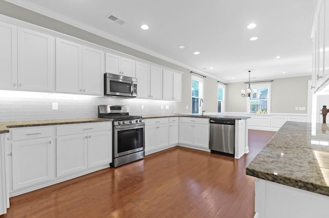 kitchen with visible vents, a peninsula, white cabinetry, a notable chandelier, and stainless steel appliances