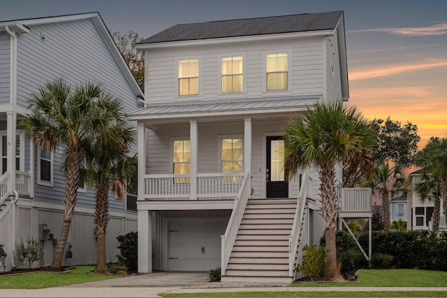 coastal inspired home with a porch and a garage