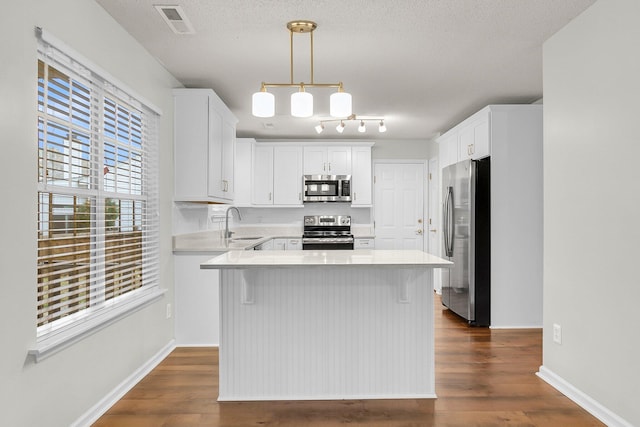 kitchen featuring white cabinets, decorative light fixtures, stainless steel appliances, and sink