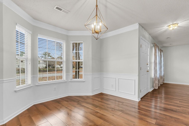 unfurnished dining area with hardwood / wood-style flooring, crown molding, a textured ceiling, and a chandelier