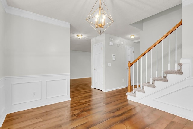 entryway featuring wood-type flooring, crown molding, and a chandelier