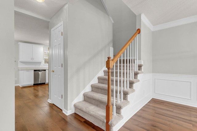 stairs featuring crown molding, hardwood / wood-style floors, and a textured ceiling