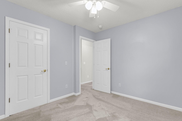 unfurnished bedroom featuring a textured ceiling, ceiling fan, and light carpet