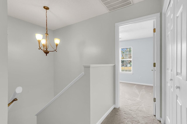 hallway featuring carpet and an inviting chandelier