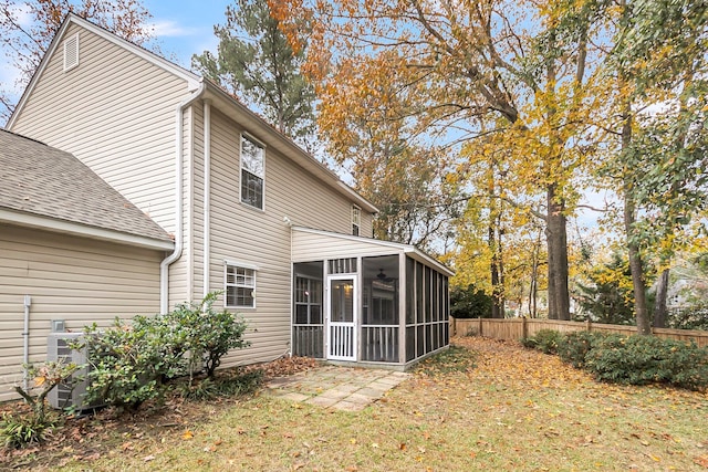 rear view of house with a lawn and a sunroom