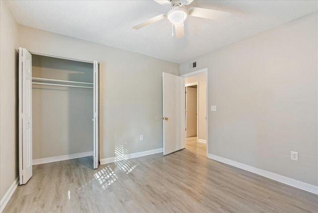 unfurnished bedroom with ceiling fan, a closet, and light wood-type flooring