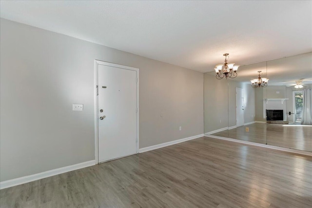 unfurnished living room with hardwood / wood-style floors and ceiling fan with notable chandelier