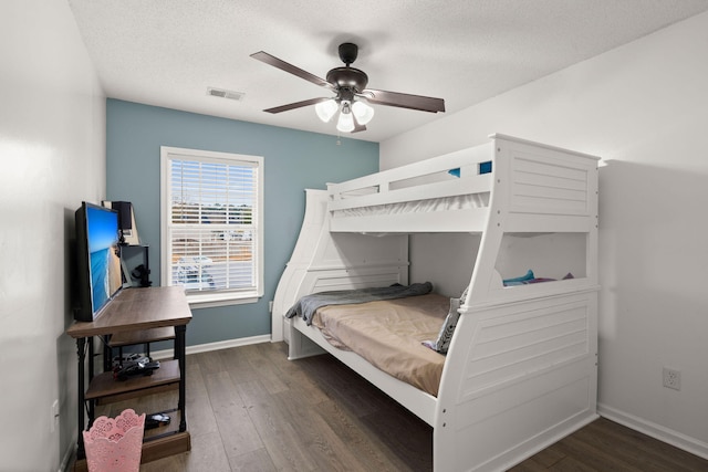 bedroom with ceiling fan, dark wood-type flooring, and a textured ceiling