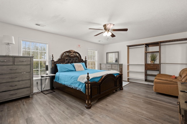 bedroom with ceiling fan, hardwood / wood-style floors, and a textured ceiling