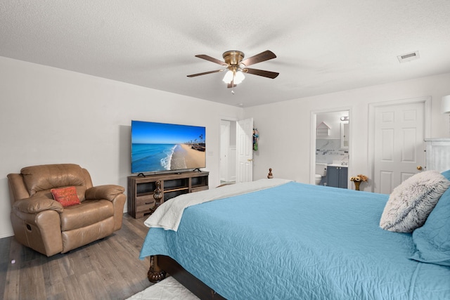 bedroom with hardwood / wood-style flooring, ceiling fan, connected bathroom, and a textured ceiling