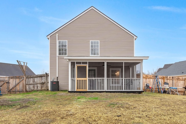 rear view of house featuring central AC unit, a sunroom, and a lawn