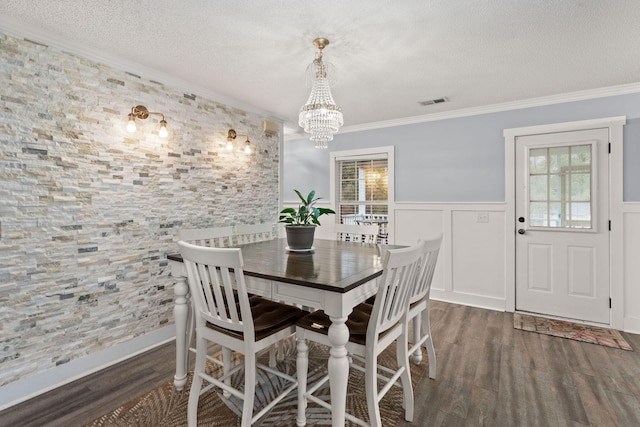 dining area featuring a notable chandelier, crown molding, dark wood-type flooring, and a textured ceiling