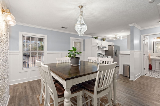 dining space featuring a chandelier, ornamental molding, dark hardwood / wood-style floors, and a textured ceiling