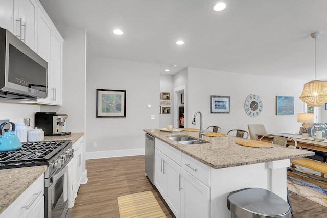 kitchen featuring sink, a breakfast bar area, a center island with sink, appliances with stainless steel finishes, and pendant lighting