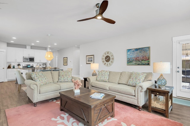 living room with light hardwood / wood-style flooring and ceiling fan