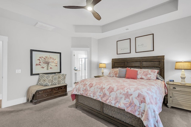 carpeted bedroom with connected bathroom, a tray ceiling, and ceiling fan