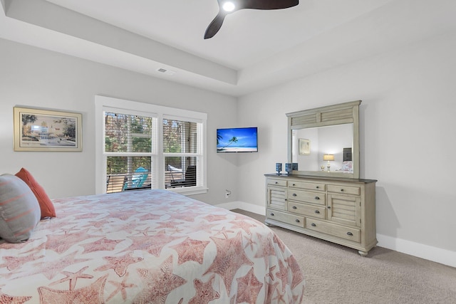 carpeted bedroom featuring ceiling fan and a raised ceiling