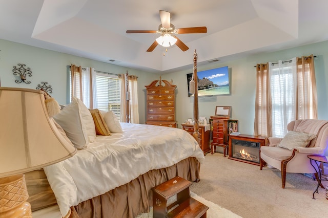 404 Norwood Ct, Moncks Corner, SC 29461 - bedroom featuring a raised ceiling, light colored carpet, a ceiling fan, and a glass covered fireplace