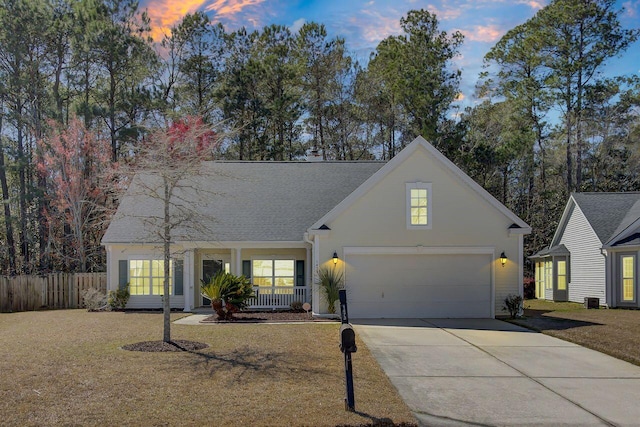 traditional-style house with fence, a porch, an attached garage, stucco siding, and concrete driveway