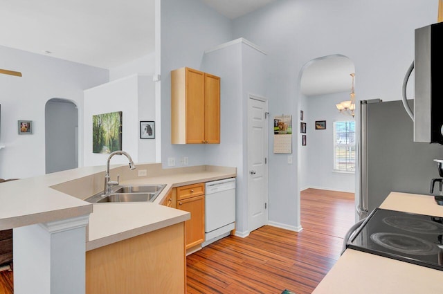 kitchen with light brown cabinets, arched walkways, appliances with stainless steel finishes, and a sink