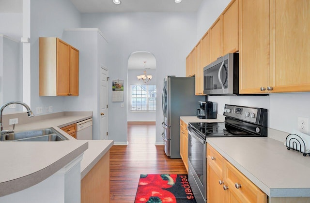 kitchen featuring light brown cabinetry, a sink, appliances with stainless steel finishes, light countertops, and dark wood-style flooring