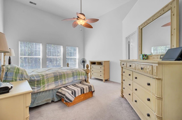 bedroom featuring visible vents, light carpet, a high ceiling, and ceiling fan