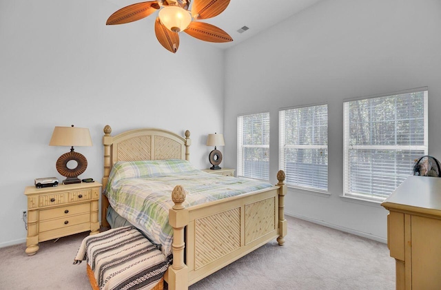 bedroom with visible vents, light colored carpet, baseboards, and ceiling fan