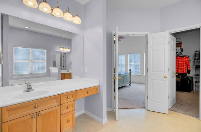 full bathroom featuring tile patterned floors, a walk in closet, baseboards, and vanity