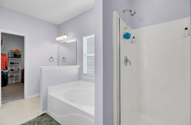 full bathroom featuring a garden tub, a spacious closet, baseboards, and a stall shower