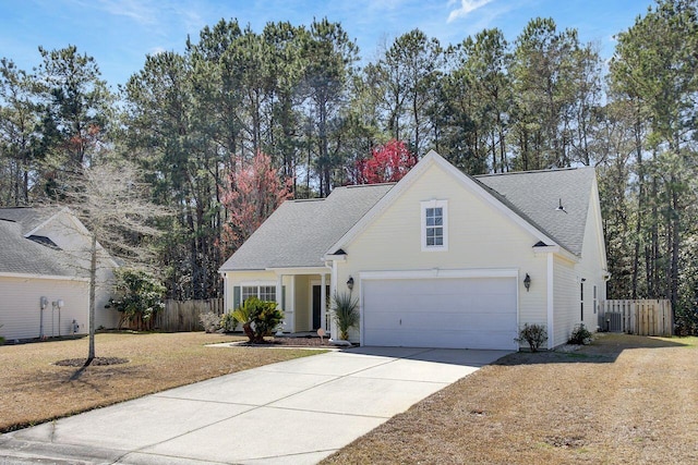 view of front of property with fence, central air condition unit, concrete driveway, a front yard, and a garage