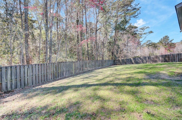 view of yard with a fenced backyard and a wooded view