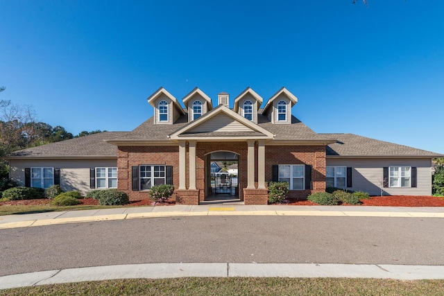 view of front of property with brick siding and a shingled roof