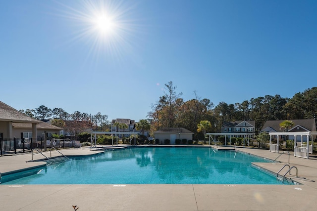 community pool with a patio, a pergola, and fence