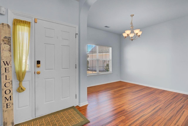 entryway with visible vents, wood finished floors, arched walkways, an inviting chandelier, and baseboards