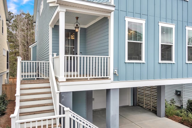 property entrance with a porch, driveway, board and batten siding, and an attached garage