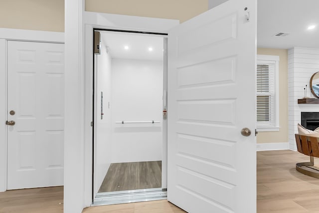 bathroom with recessed lighting, wood finished floors, visible vents, and a large fireplace