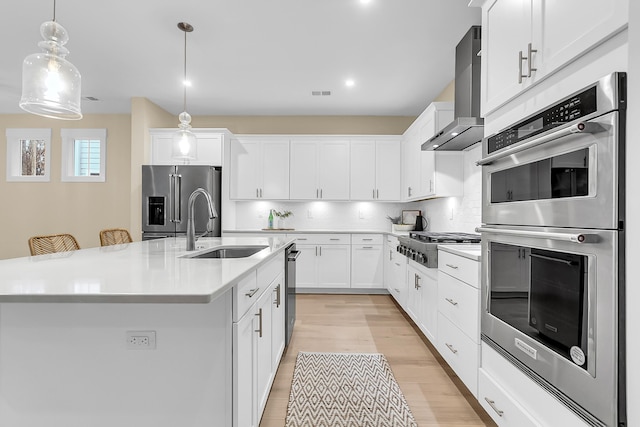 kitchen with light countertops, decorative backsplash, stainless steel appliances, wall chimney exhaust hood, and a sink